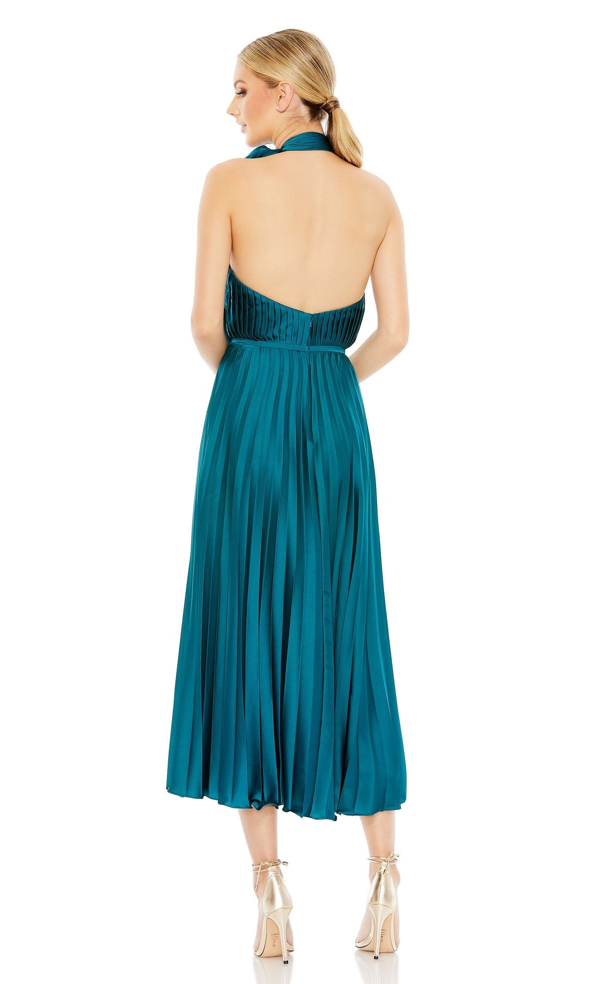 A woman faces away, wearing the Tea Length Formal Dress 26909 by Mac Duggal in teal with pleats, a halter-neck, and open back, paired with light-colored high heels.
